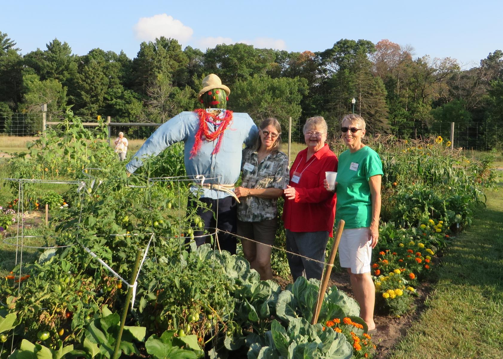 people in the community garden next to scarecrow